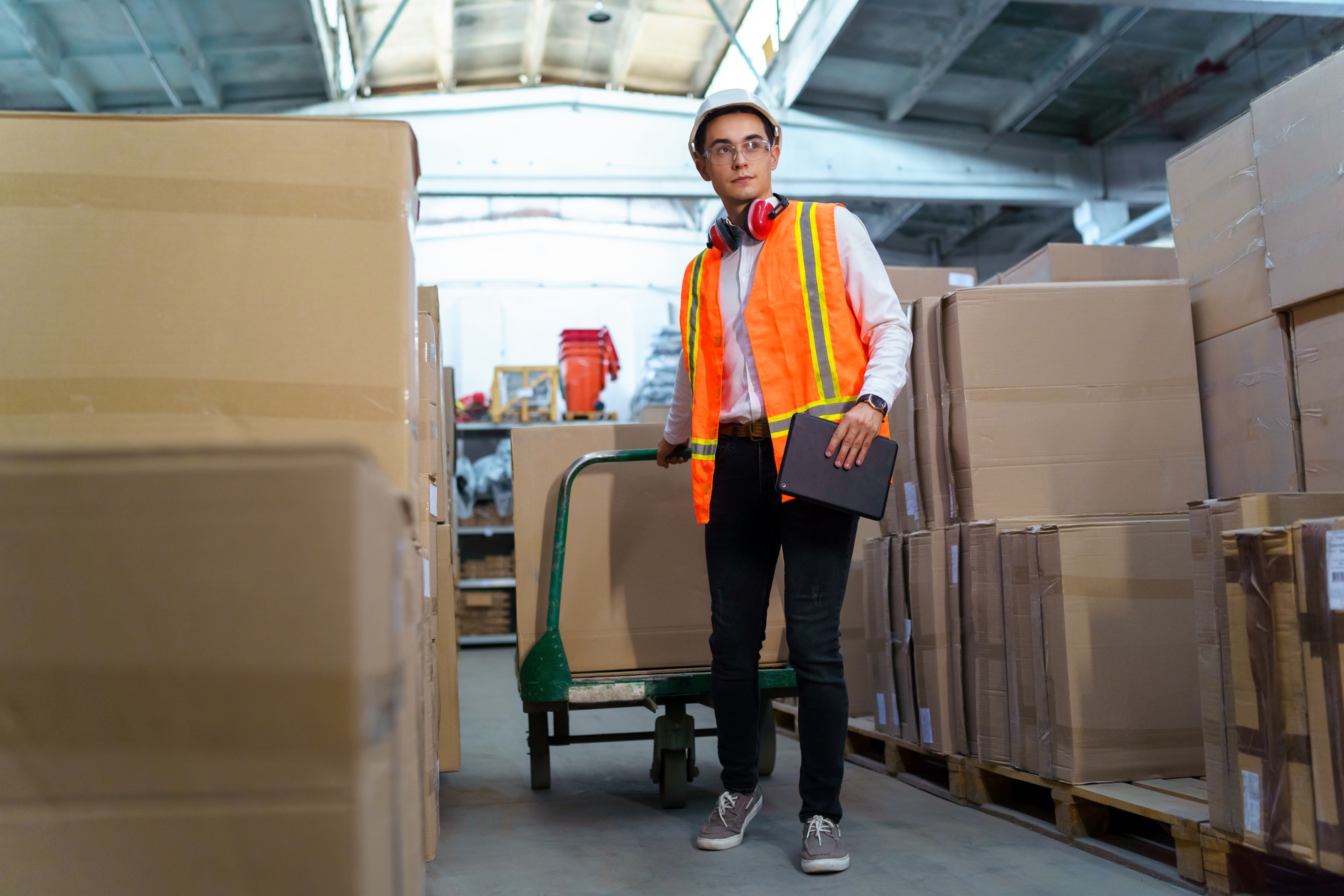 Logistic warehouse worker delivering boxes on a trolley